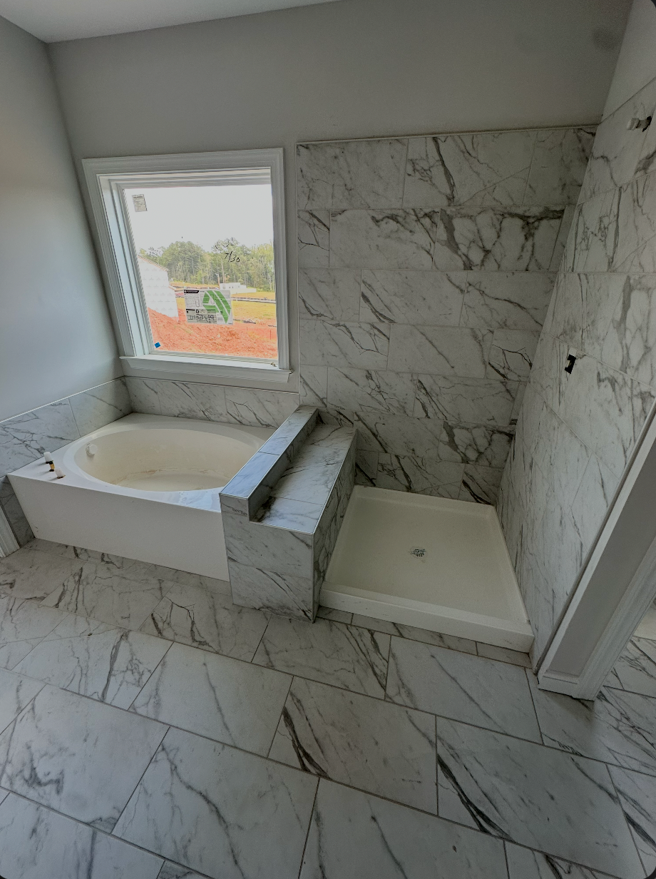 Bathroom with marble-look floor and wall tile surrounding a tub and separate shower